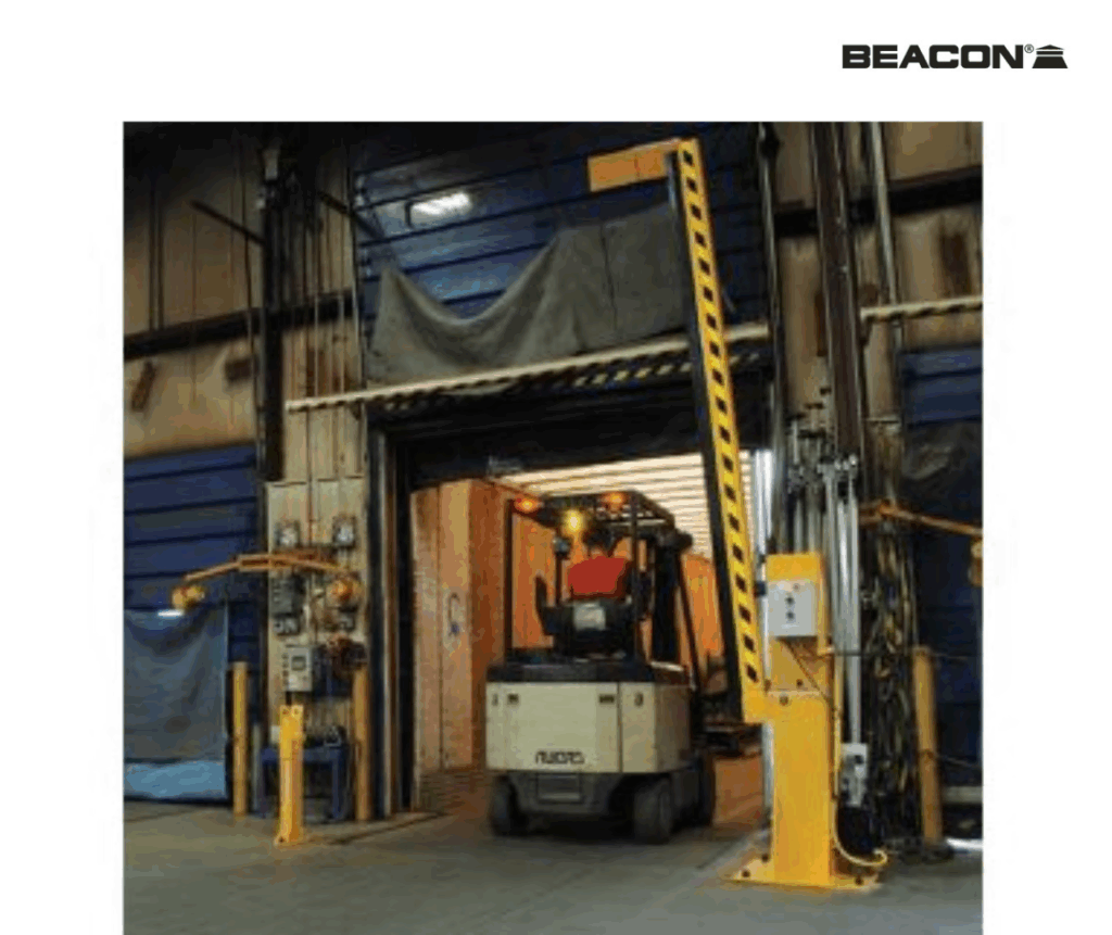 Forklift entering a loading dock in an industrial warehouse with safety barriers and overhead equipment.